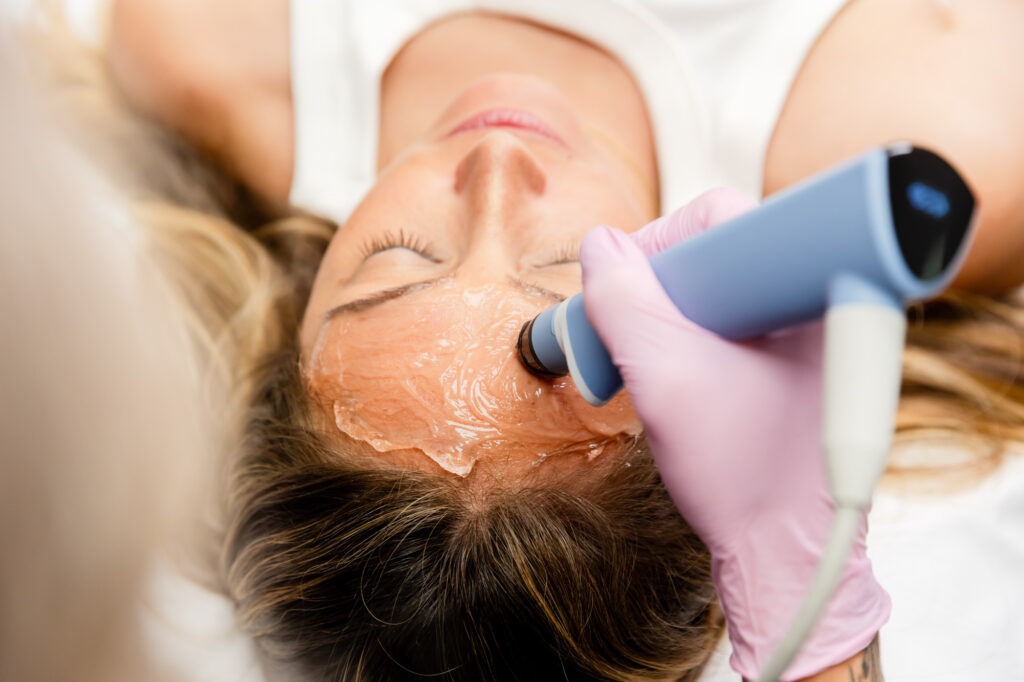 a medical professional wearing pink gloves performs an exion facial in Fargo on a female patient