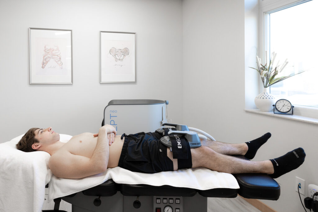 A male patient lies down and relaxes whil receiving Emsculopt body contouring in Fergus Falls