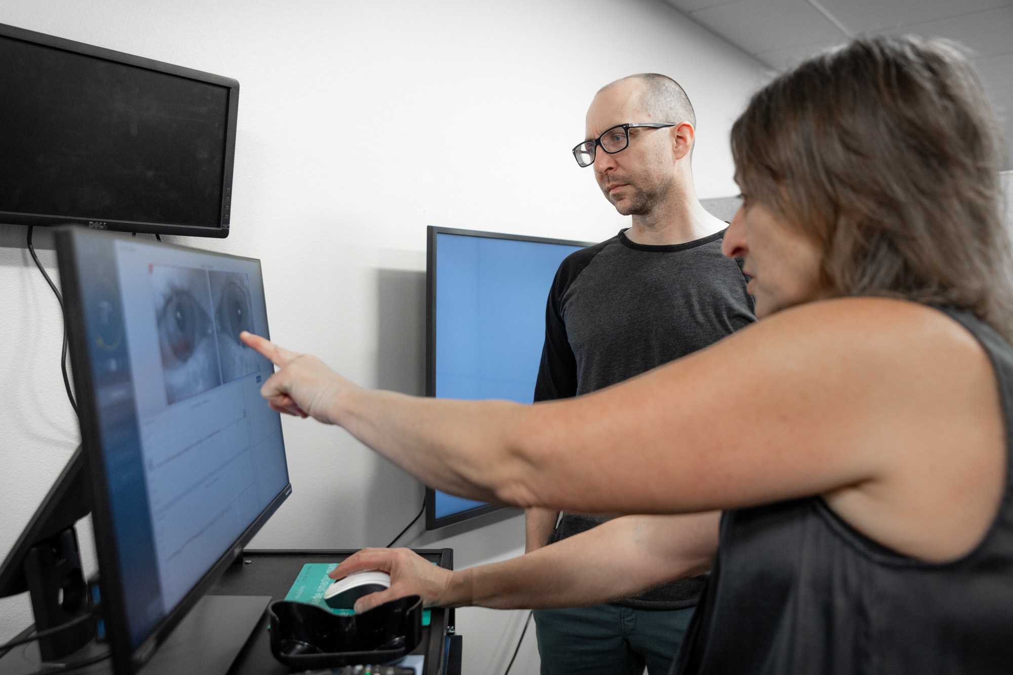 A doctor points to a screen while discussing concussion therapy in Fargo with a male patient